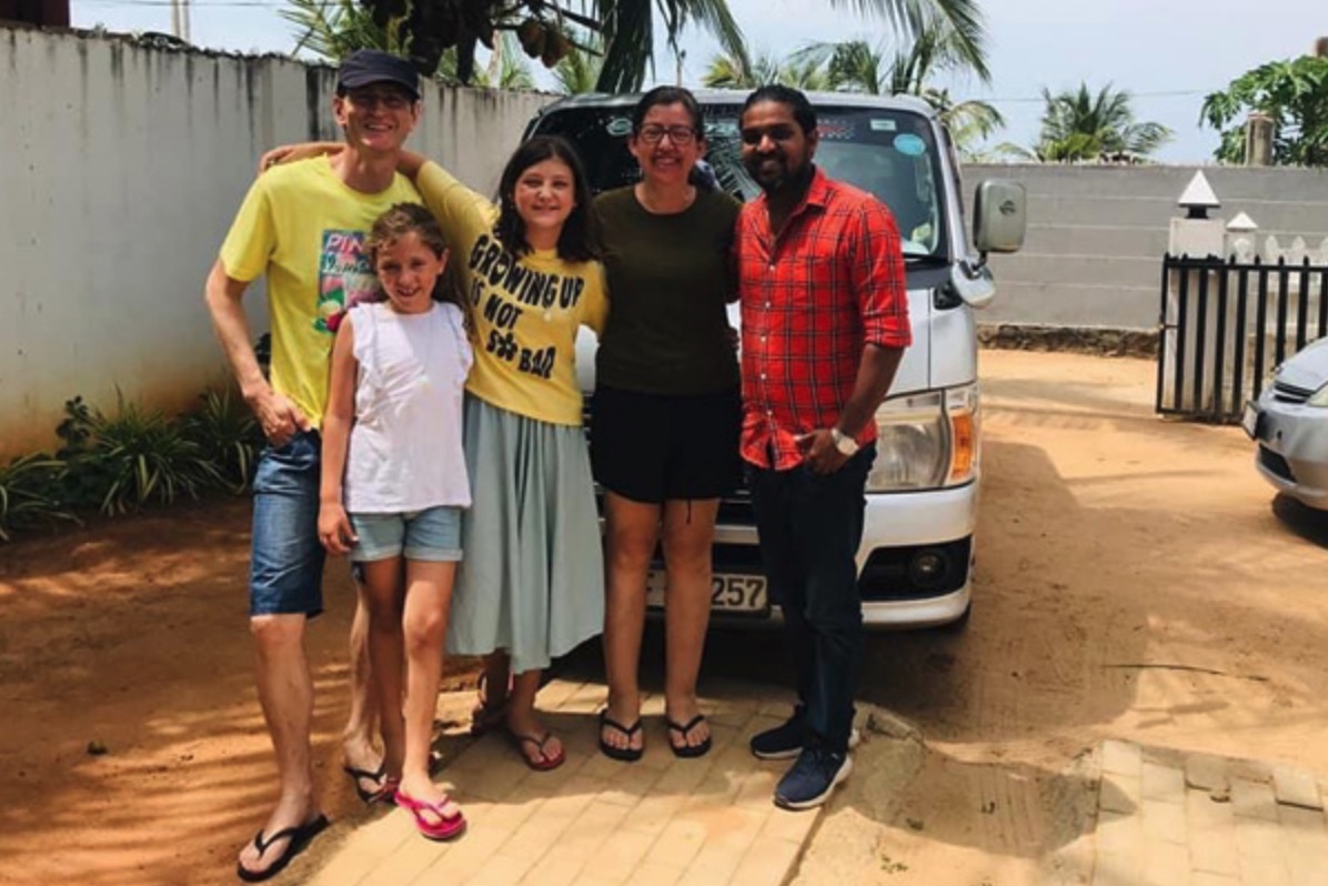 A family with their private driver beside a white charter van in Sri Lanka