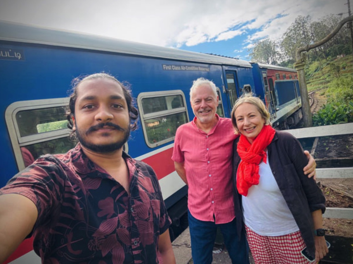 An older couple with their private driver beside a scenic train in Sri Lanka