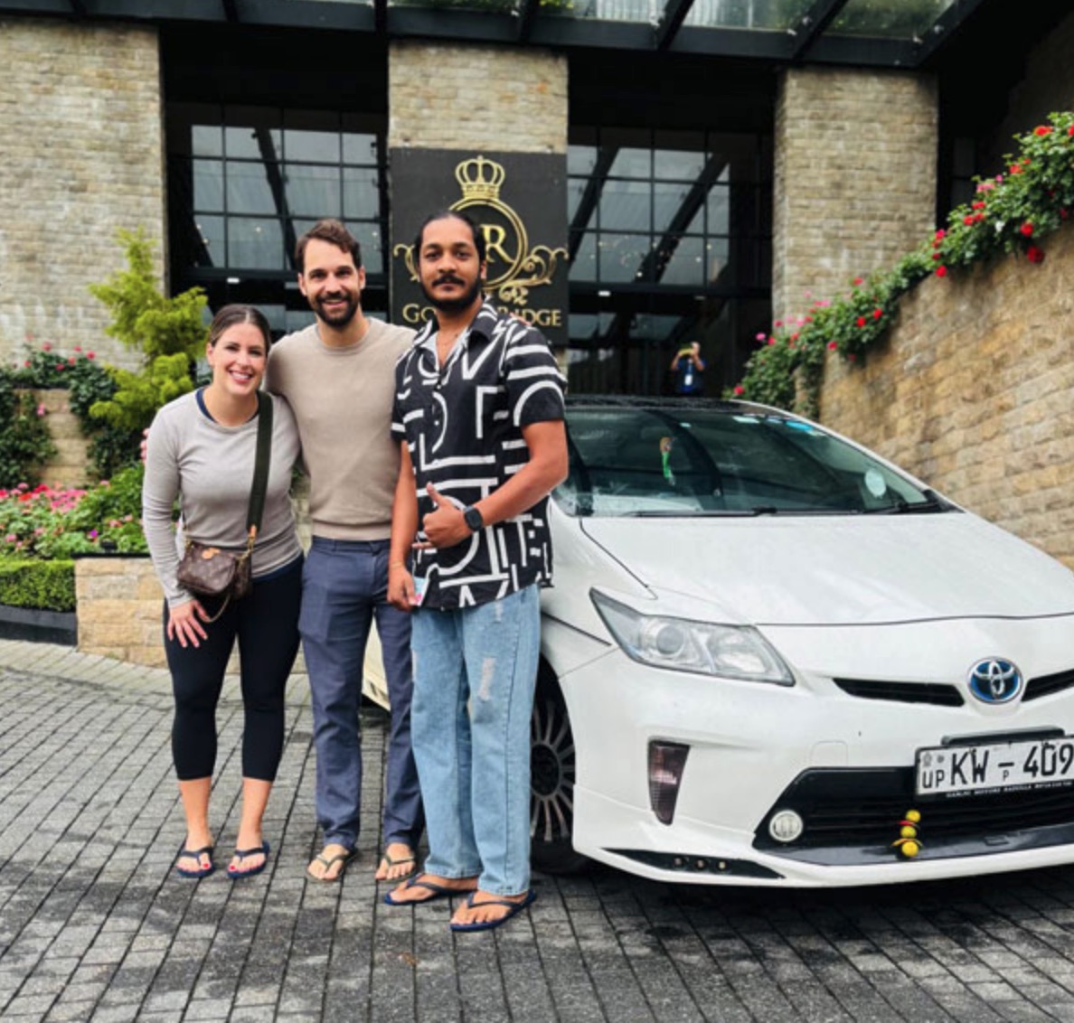 A couple with their private driver beside a white car at a Sri Lanka hotel