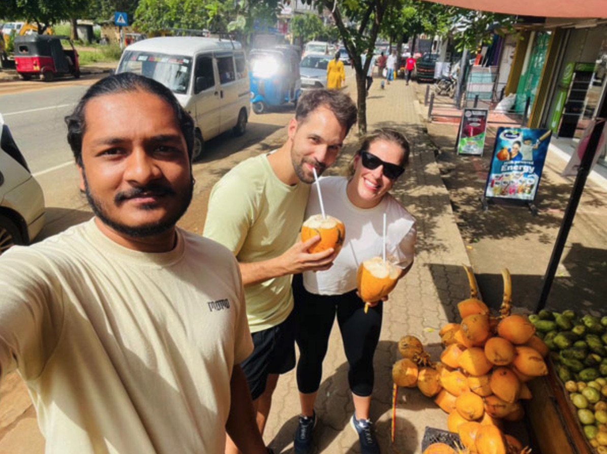 A couple and their private driver enjoying coconuts during a Sri Lanka road trip