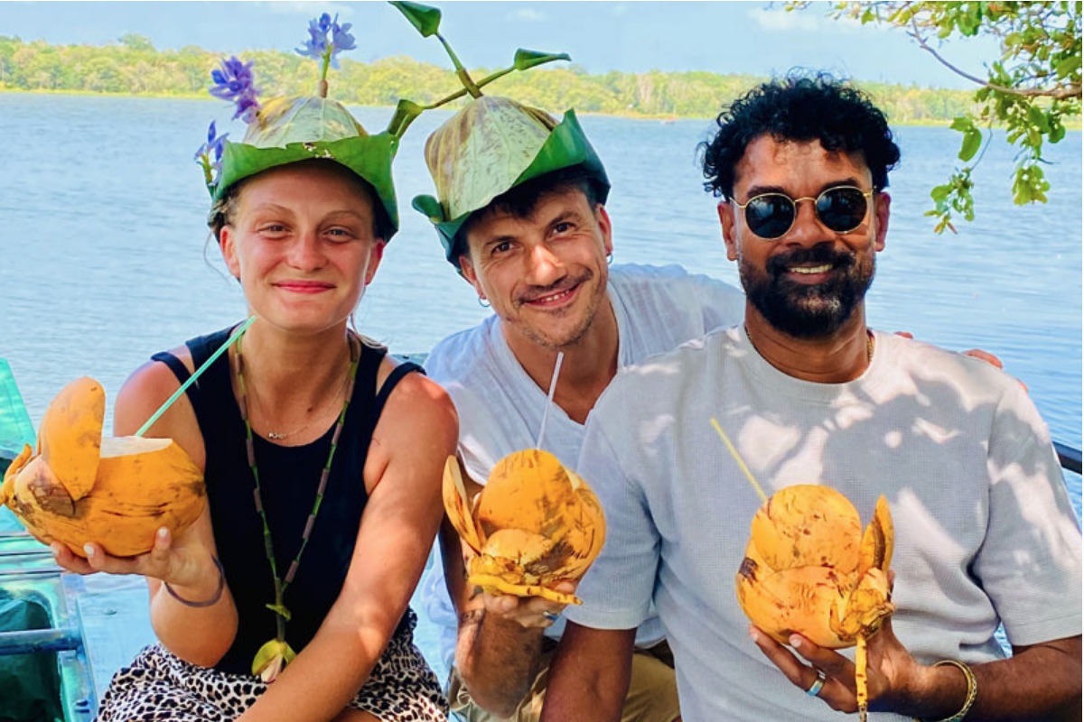 Two travellers and their private driver enjoying coconuts beside the water in Sri Lanka