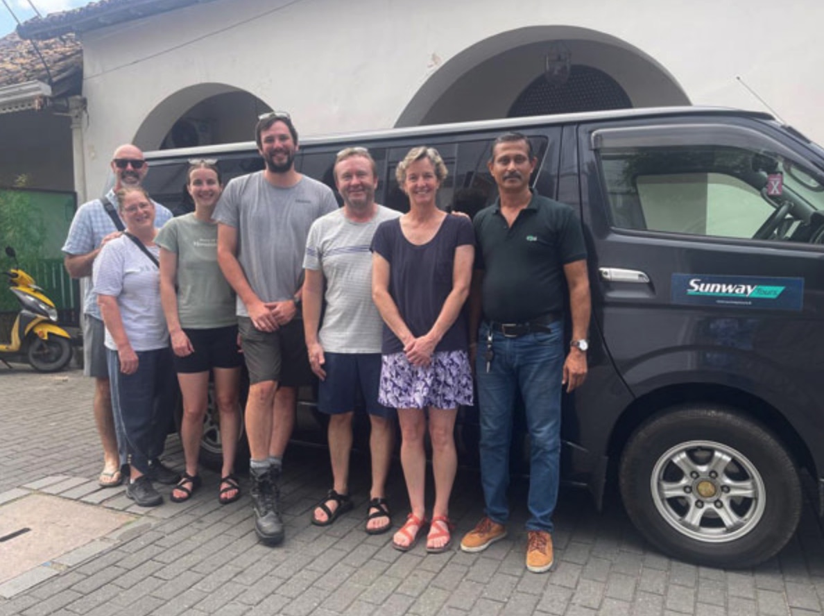 A group of travellers with their private driver beside a charter van in Sri Lanka